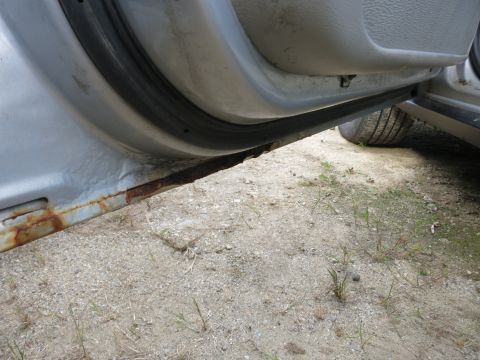 1991 Ford LTD Crown Victoria - The door sill of a vehicle shows significant rust, with a tire visible in the background.