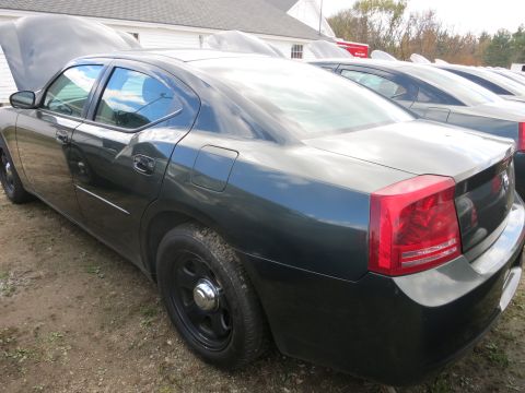 1991 Ford LTD Crown Victoria - Rear view of a dark sedan, possibly a police vehicle, with its hood open and parked in a lot with other similar vehicles.