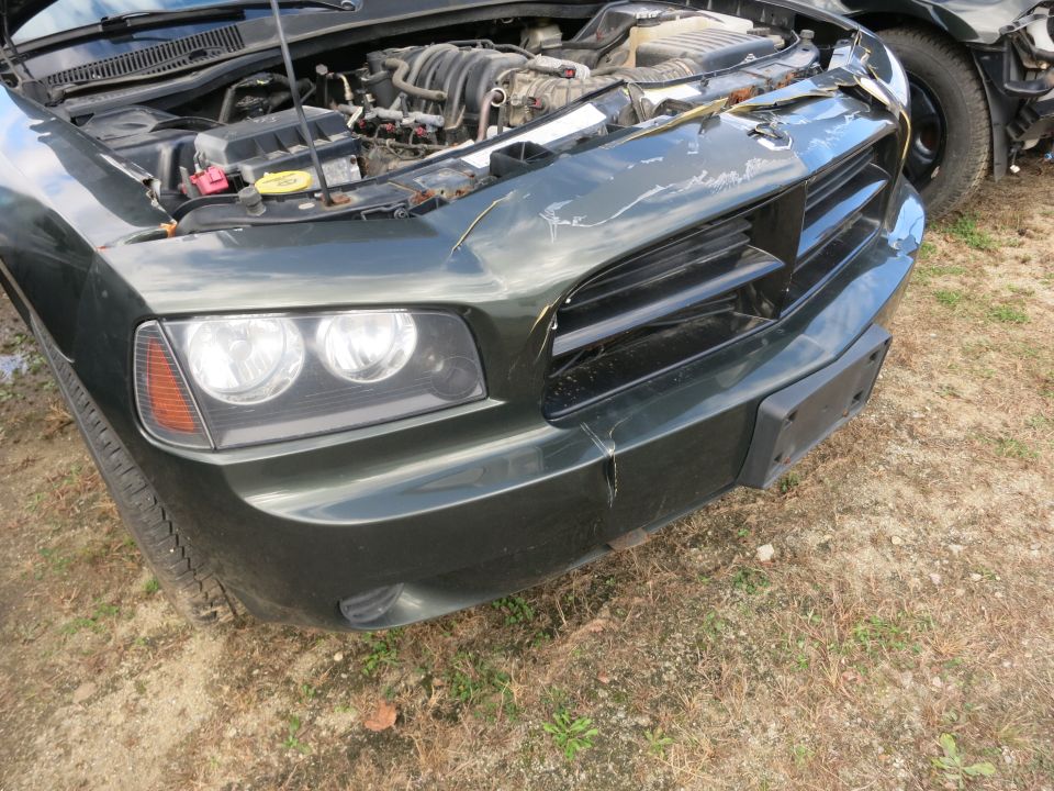 Front end of a sedan with damaged bumper cover at an outdoor lot