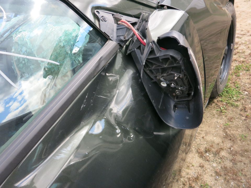 Sedan front fender with broken-off side mirror exposing wiring