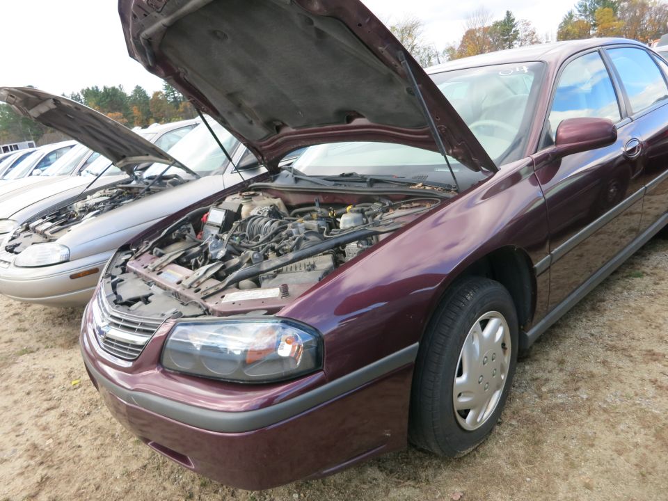 Maroon Chevrolet sedan with hood raised showing engine at a lot