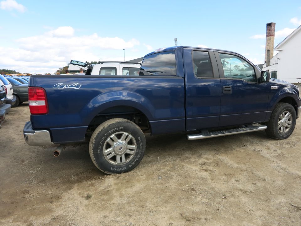 Blue Ford F-150 4x4 pickup truck, rear three-quarter view at a lot