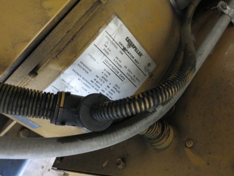 1991 Ford LTD Crown Victoria - Caterpillar generator-set nameplate showing engine model, kW rating and generator data, partly obscured by flexible conduit.