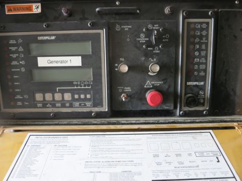 1991 Ford LTD Crown Victoria - Photograph of a Caterpillar generator control panel with a partial diagnostic-codes reference card resting below it.