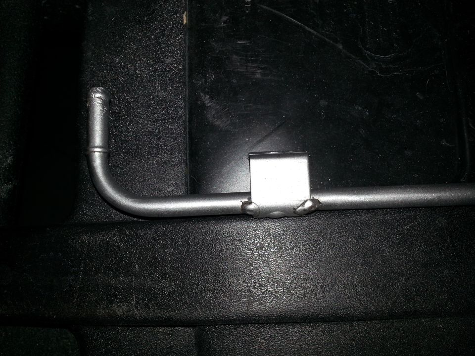 Photo of a bent metal bar or sway bar resting against dark trim
