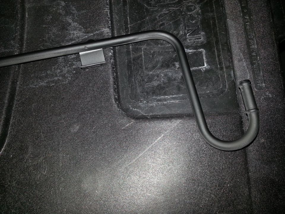 Photo of a black bent metal bar with a clip on a truck bed liner