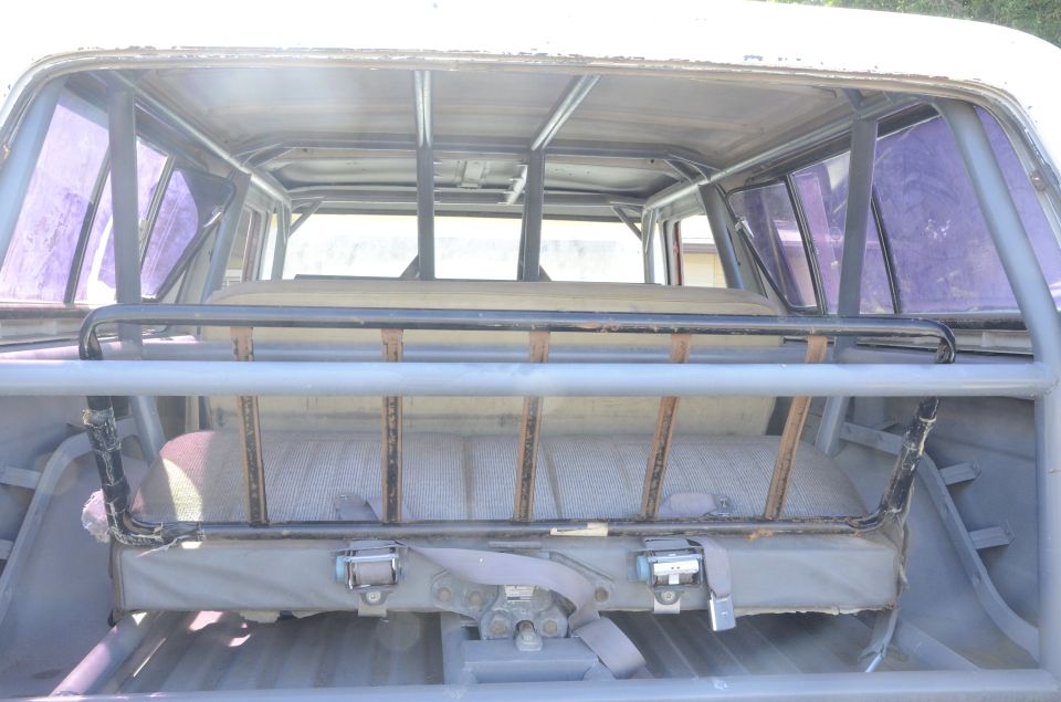Rear interior view of a vehicle with a roll cage and bench seat.