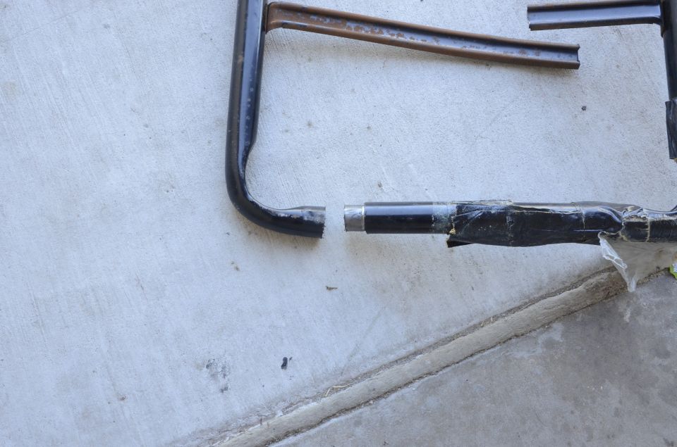 Broken black metal tube with exposed metal and black tape.