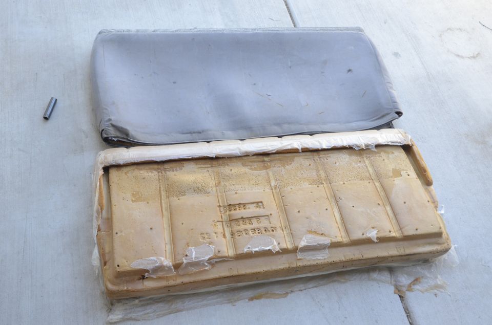 Old gray sun visor next to its yellowed foam backing panel laid on concrete