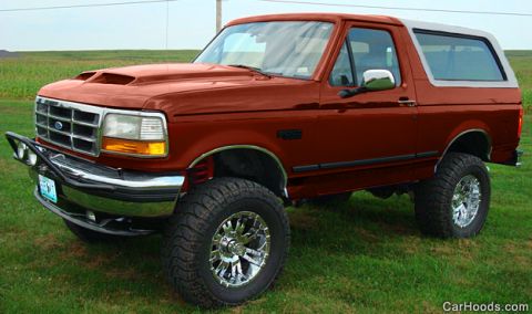 1994 Ford Bronco - Photograph of a lifted orange Ford Bronco on chrome wheels, not a technical document.