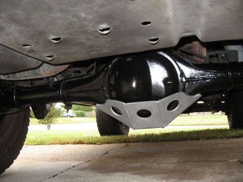 1994 Ford Bronco - The underside of a 1994 Ford Bronco shows a black painted rear differential with a silver skid plate bolted to it, viewed from a low angle.