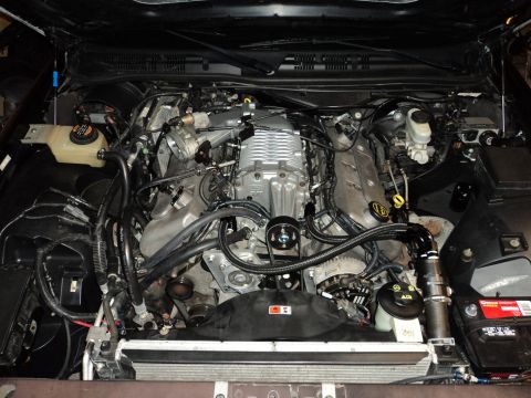 2004 Mercury Grand Marquis - A heavily modified V8 engine bay is shown, featuring a prominent silver supercharger and various aftermarket hoses and components.
