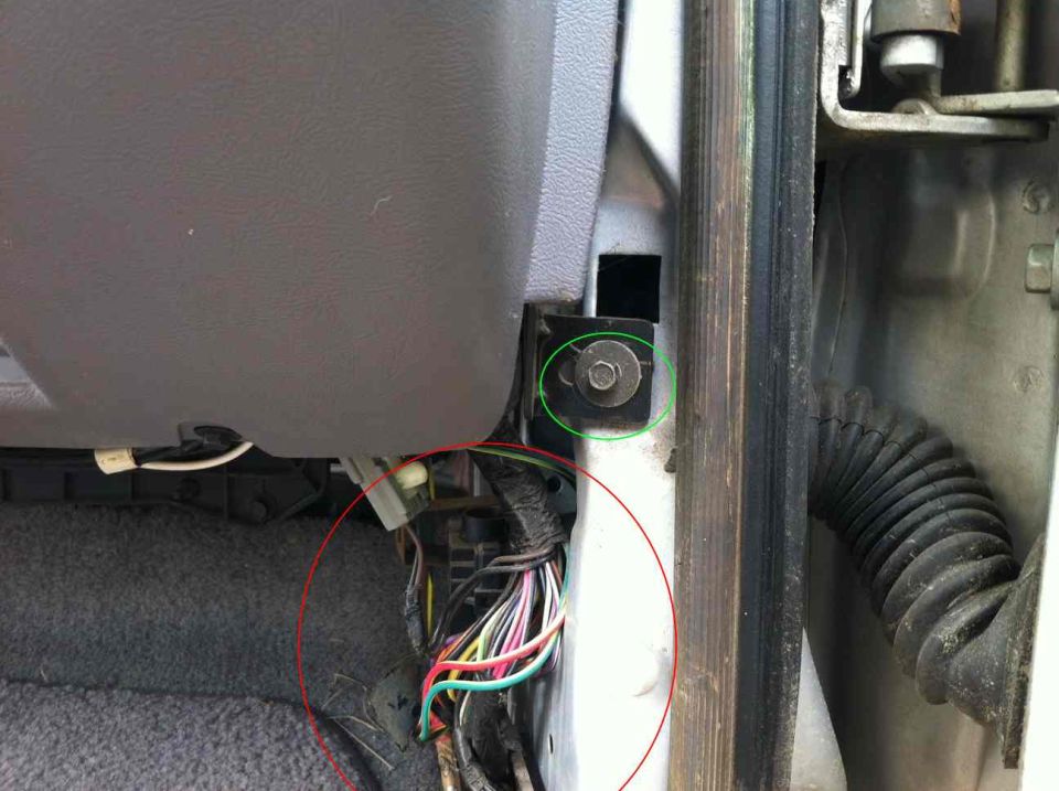 Close-up of a vehicle's interior door panel and dashboard area, showing some exposed wiring