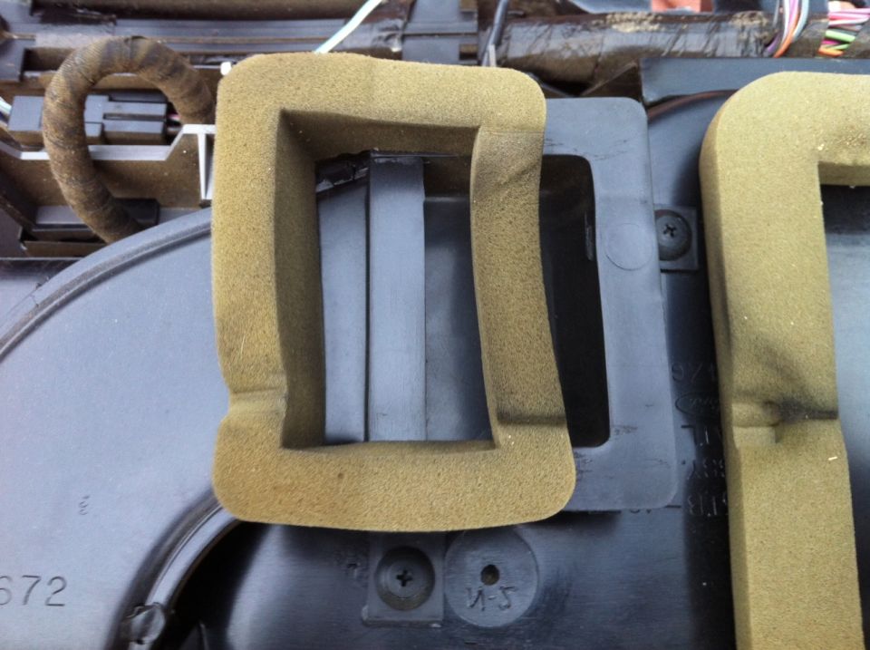 Tan foam insulation around a black plastic vent assembly.