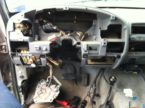 1996 Ford F-150 - The interior of a vehicle's dashboard is exposed, revealing complex wiring and internal components during a repair or modification.