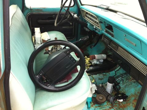 1996 Ford F-150 - The interior of a vintage truck shows a turquoise dashboard and seats, with a steering wheel resting on the passenger seat.