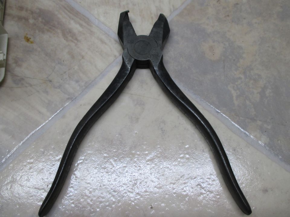 old black pliers on a tiled floor