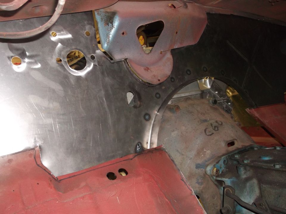 Car interior firewall with new metal patch panels being fitted. Some rust and red primer visible