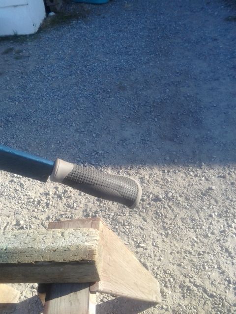 1991 Ford Bronco - A close-up shot focuses on the grip of a tool, with gravel and wooden beams in the background.