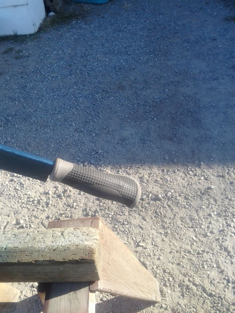 Close-up of a textured handle on a blue tool, resting on wooden supports
