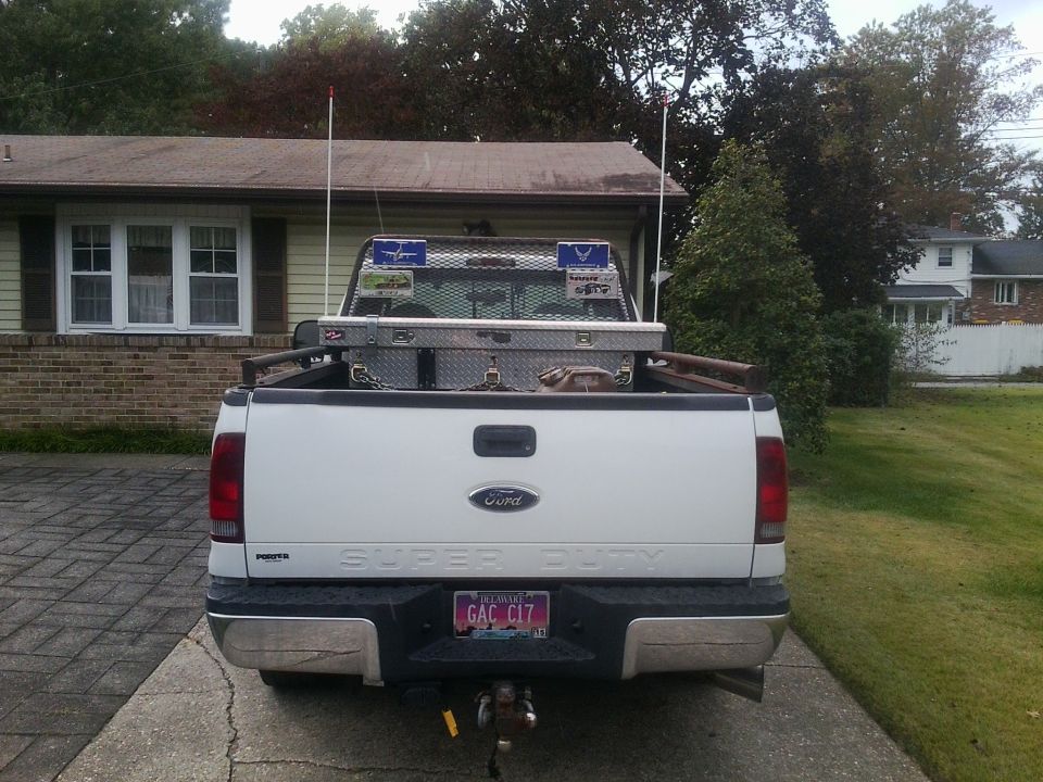 Rear view of a white Ford Super Duty pickup truck with a toolbox in the bed and a custom license plate
