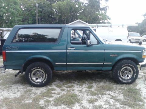 1996 Ford Bronco - Side profile of a green 1996 Ford Bronco with chrome trim and 4x4 badging.