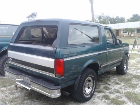 1996 Ford Bronco - Rear view of a 1996 Ford Bronco parked outdoors with another vehicle to its left.