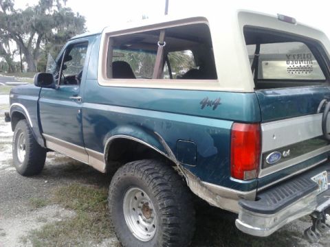 1996 Ford Bronco - This green Ford Bronco has tan trim and visible damage to its rear fender.