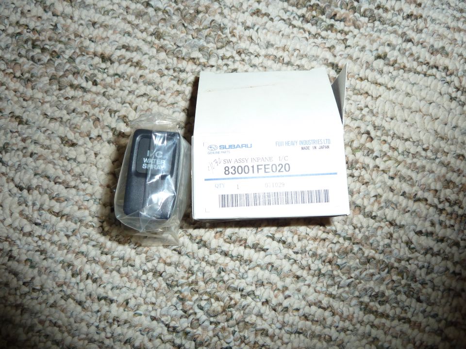 Subaru water spray switch in packaging next to its box with part number 83001FE020