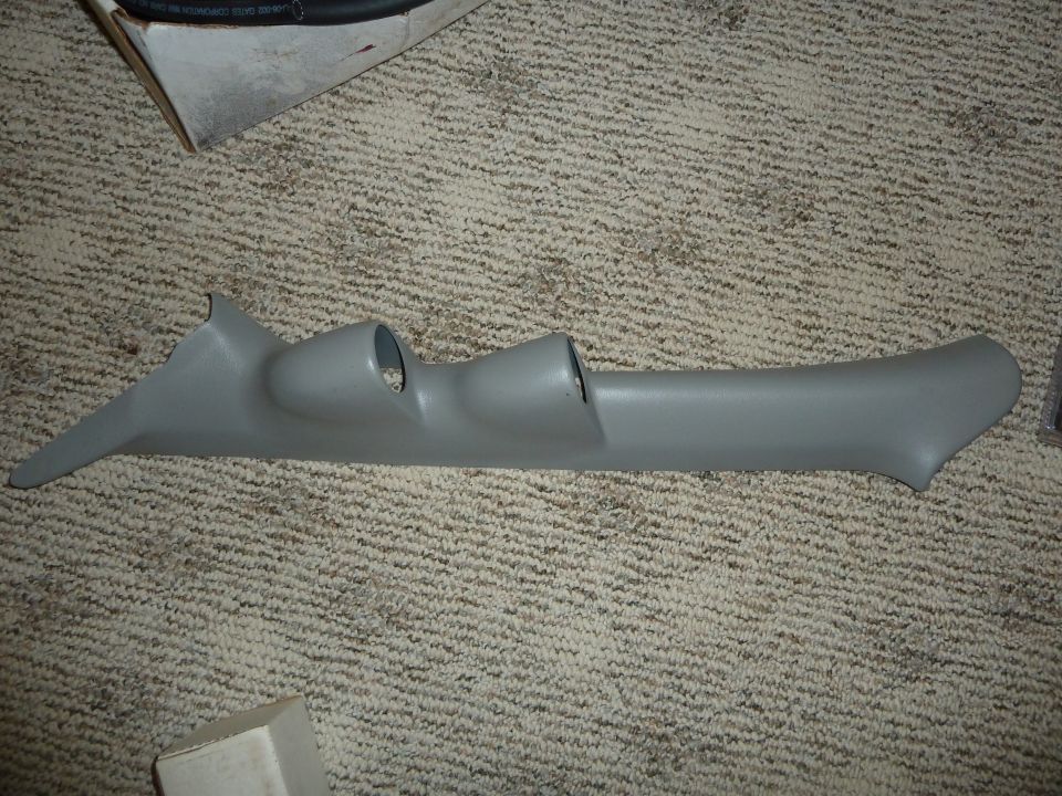 Gray plastic A-pillar gauge pod with two openings, lying on carpet
