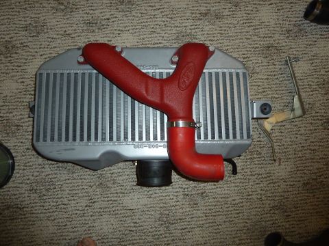 2007 Subaru Impreza - A red intercooler piping assembly is shown connected to a silver intercooler, resting on a carpeted surface.