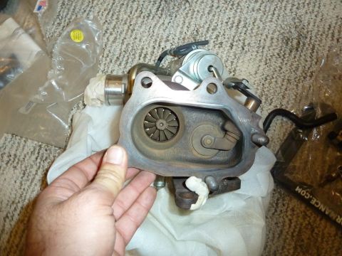 2007 Subaru Impreza - A turbocharger is held for inspection, with "SUPERMOTORS.NET" visible on a black hose in the background.