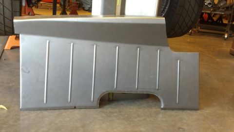 1964 Ford Fairlane - A fabricated metal panel, likely for a car's floor, sits on a concrete surface in a workshop.