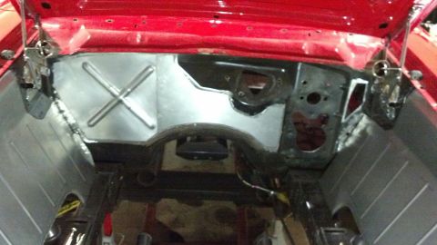 1964 Ford Fairlane - Close-up view of a red car's engine bay firewall, showing metal bracing and structural components.